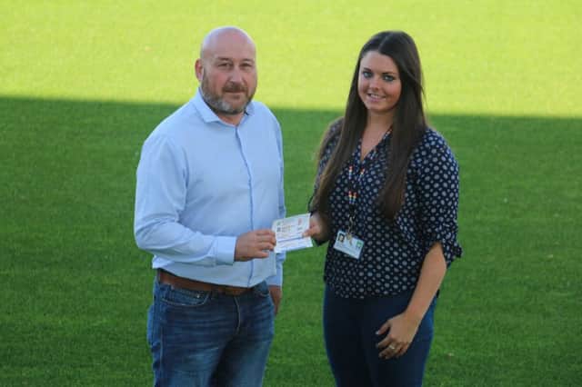 Hartlepool United operations director Mark Burrows hands over the tickets to Hartlepool Borough Council education officer Lucy Cumming.