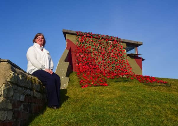 Heugh Gun Battery manager Diane Stephens with the Yarn Bombers crotcheted poppies