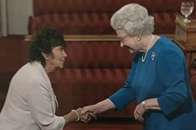 Wendy McLoughlin receives her MBE from the Queen.