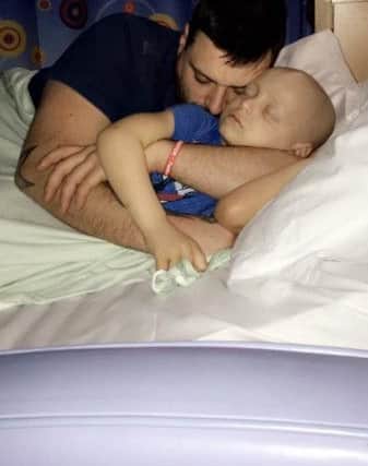 Bradley is given cuddles in his hospital bed by dad Carl.