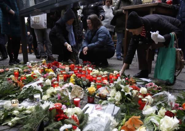 People place flowers near the crime scene in Berlin, Germany, Tuesday, Dec. 20, 2016, the day after a truck ran into a crowded Christmas market and killed several people. (AP Photo/Matthias Schrader)