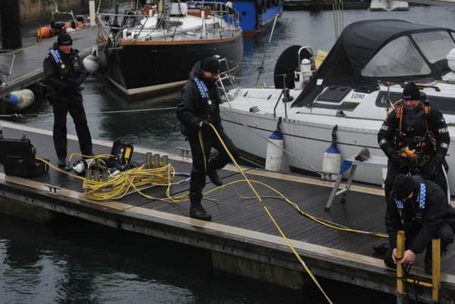 Police divers work at the marina as they try and find Andrew Roy.