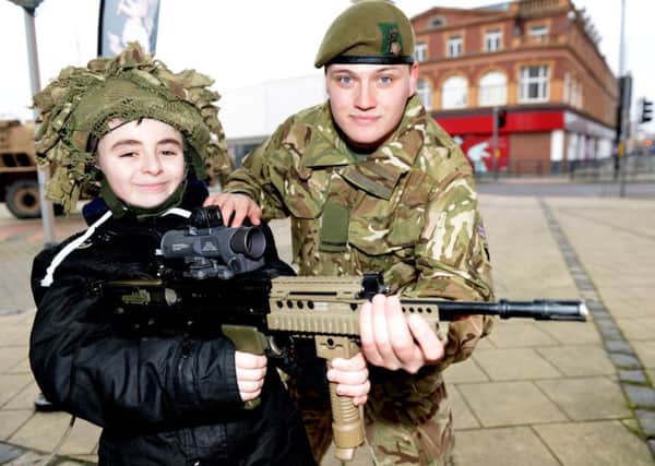 Private Sam Neal with Gary-Lee Parker (10) from  Burn Valley gets to grips with the SA80 A2 weapon he visited Army display in Church Square, Hartlepool. Picture by FRANK REID