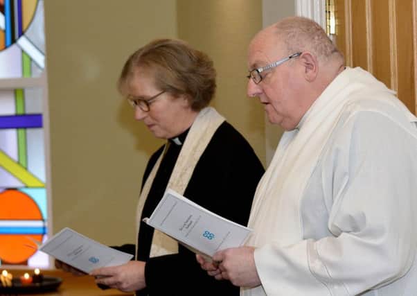 Reverend Janet Burbury listens as Father Jim Angus conducts closing prayers during the re-dedication service.
