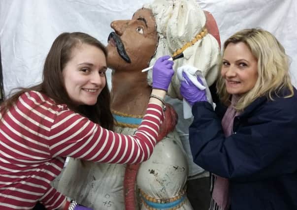 Volunteer Sarah Morris, left, and curator Clare Hunt give some care to the figurehead.