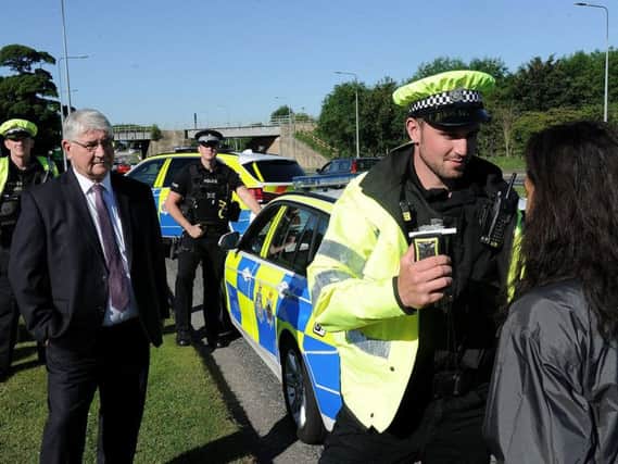 Acting police sergeant Aaron Leathley gives a roadside breath test on the A690 as police crime and victim commissioner Ron Hogg and police officers look on.
