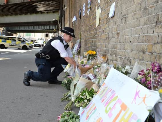 A police officer lays some flowers passed over by a member of the public, close to Finsbury Park Mosque in north London, after one man died and eight people were taken to hospital and a person arrested after a rental van struck pedestrians. Picture by John Stillwell/PA Wire