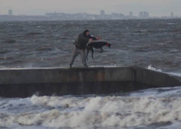 Image sent in by Mail reader of man appearing to throw dog into the sea.