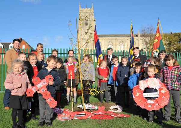 Pupils from Brougham Primary School place poppy wreaths beside the tree in memory of former teacher Joseph Jobling.