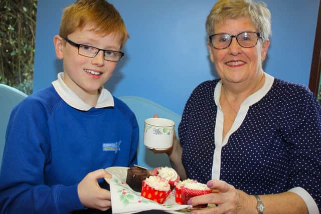 Support staff member and housekeeper at Eldon Grove Academy,  Margaret Foster, 71, is served up a treat by pupil Thomas Callaghan, 10.