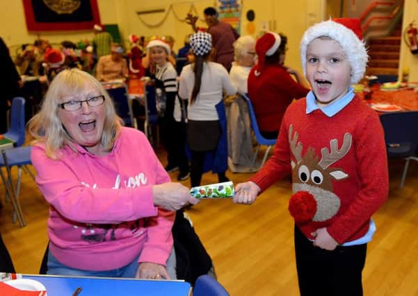 Thornley Primary school pupil Lewis Dowding (7) pulls a cracker with Heather Lonsdale (64) during the OAP Christmas party.