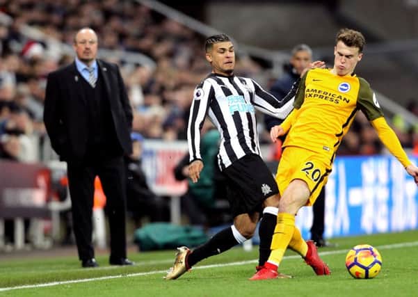 Newcastle Uniteds DeAndre Yedlin challenges Brighton & Hove Albions Solly March, while Rafa Benitez watches on in the background.