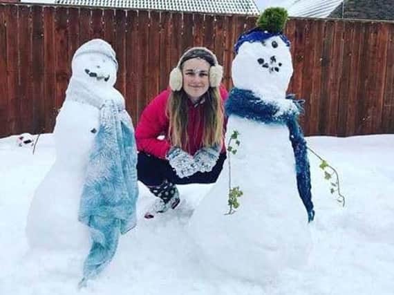 Alison Foster posing with a pair of snowmen.