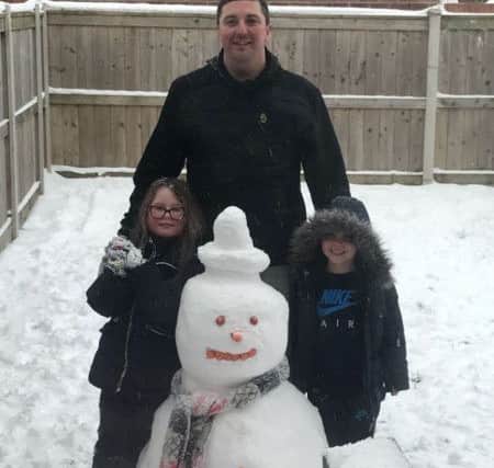 Poppie-Mae Hull and Hunter Hull with their snowman and dad Daniel Hull.
