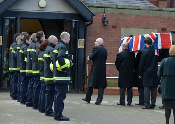 Firefighters form a guard of honour as the coffin enters the building.