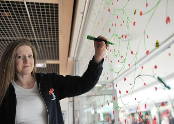 Artist Jolene Elms putting the finishing touches to the decorated window in the Forces Support shop in Middleton Grange Shopping Centre. Picture by FRANK REID